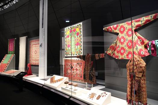 Diese mehr als 6 m hohe Wandvitrine zeigt Buddhistische Textilkunst. Gebogenes Glas.